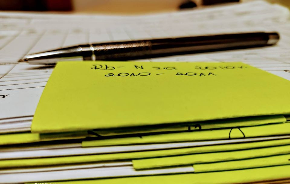 Stos żółtych karteczek samoprzylepnych z odręcznymi notatkami leżący na arkuszu kalkulacyjnym, obok czarne pióro.