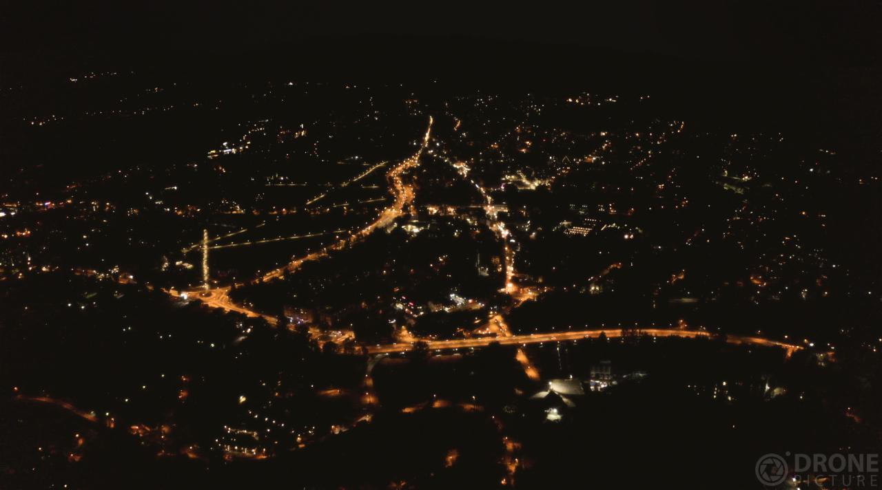 Nocny widok z lotu ptaka na miasto oświetlone pomarańczowymi światłami ulic i budynków, wykonany dronem.