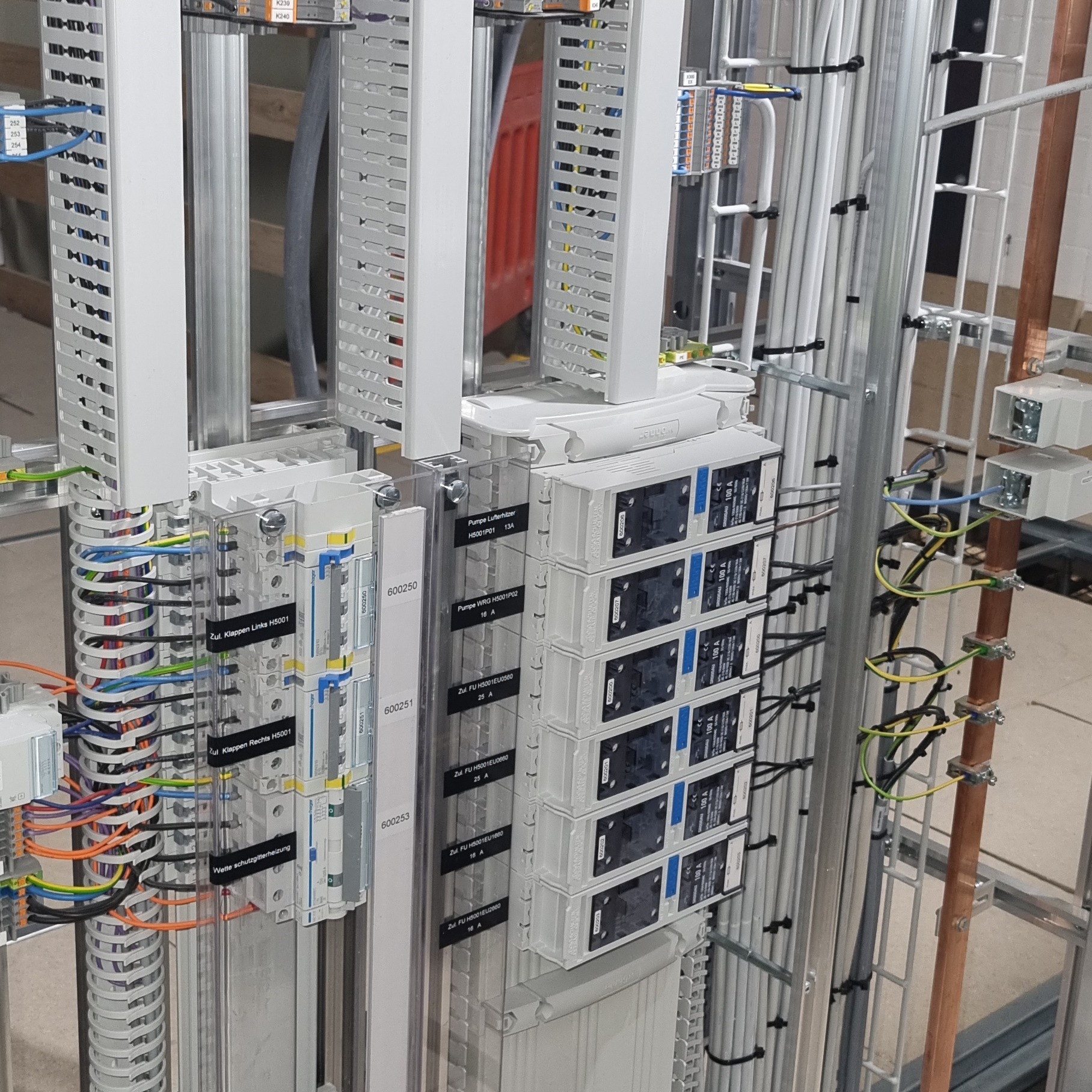 Szczegółowe ujęcie rozdzielnicy elektrycznej w Gdańsku, widoczne liczne przewody, zabezpieczenia i oznaczenia na listwach. Uporządkowane kable w metalowej konstrukcji.