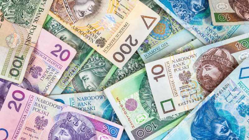 Stos banknotów polskich złotych o różnych nominałach (10, 20, 100, 200) ułożonych warstwami, tworzących chaotyczny, ale bogaty wizualnie wzór.