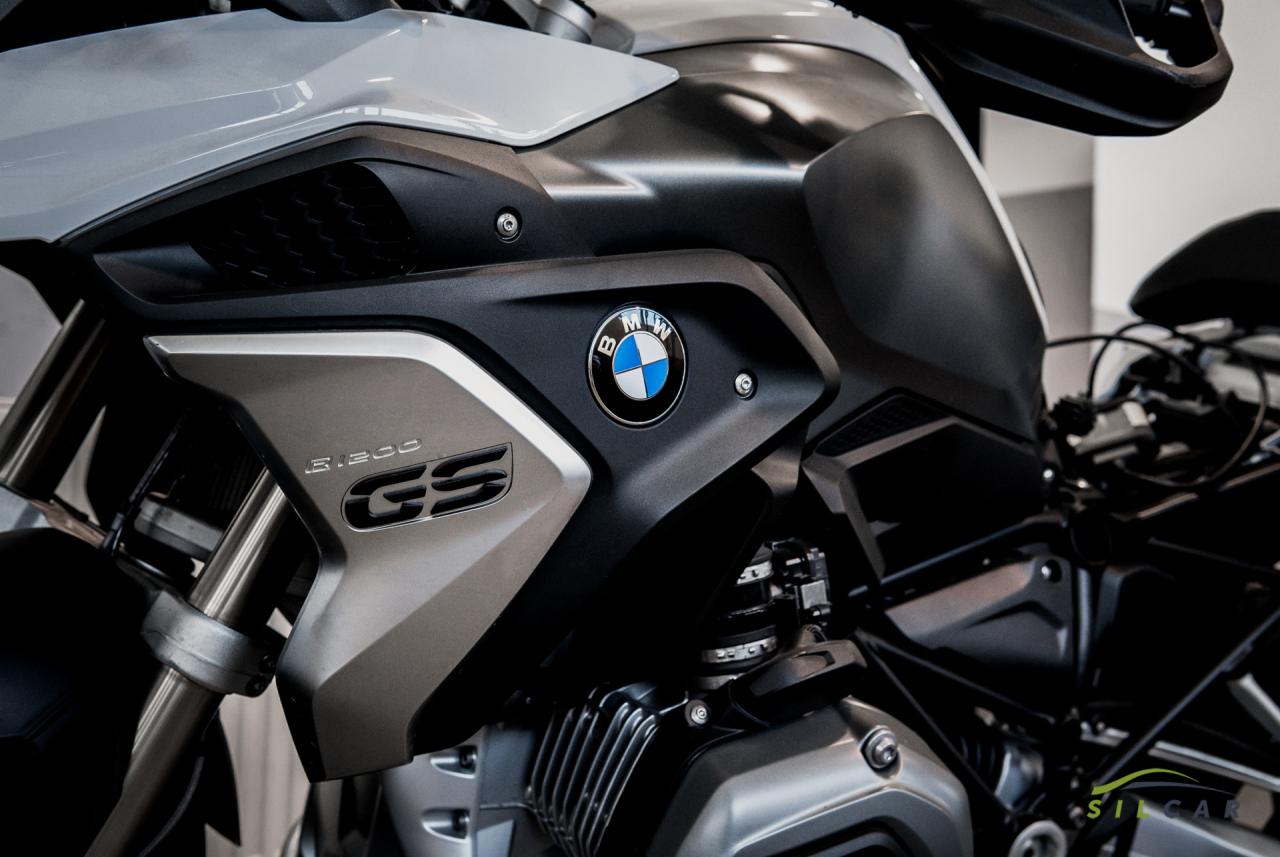 Szczegółowy widok motocykla BMW R 1200 GS z widocznym logo, srebrnym panelem bocznym i elementami silnika, uchwycony w neutralnym oświetleniu.