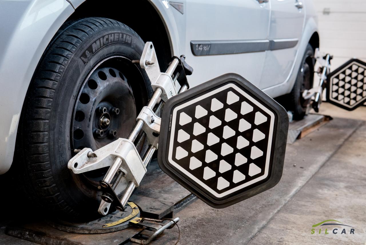 Srebrny samochód na stanowisku do geometrii kół z założonymi tarczami pomiarowymi na przednich kołach, widoczny profil opony Michelin.