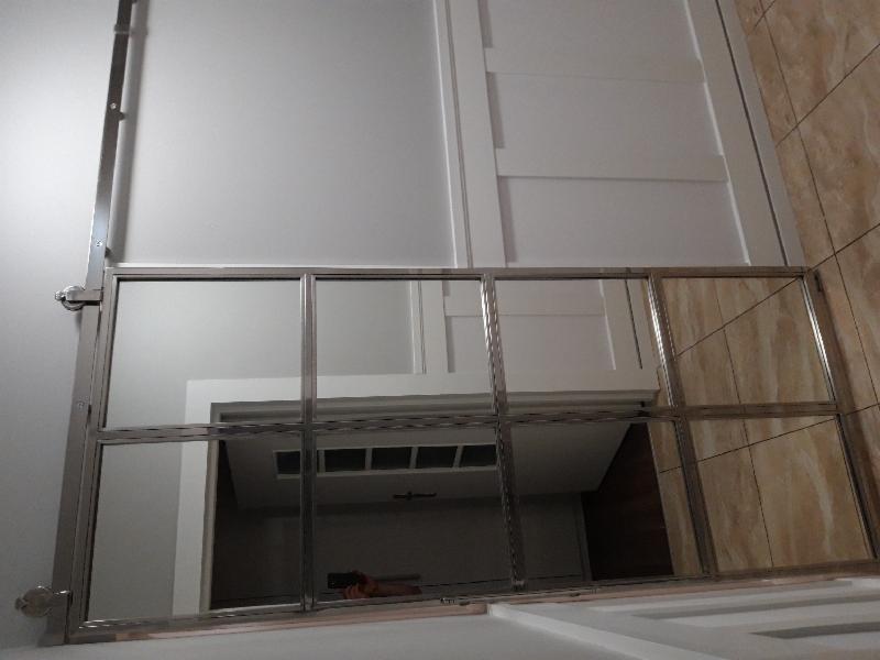 Szklana balustrada z metalowymi ramami, widok z dołu, z odbiciem wnętrza pomieszczenia.