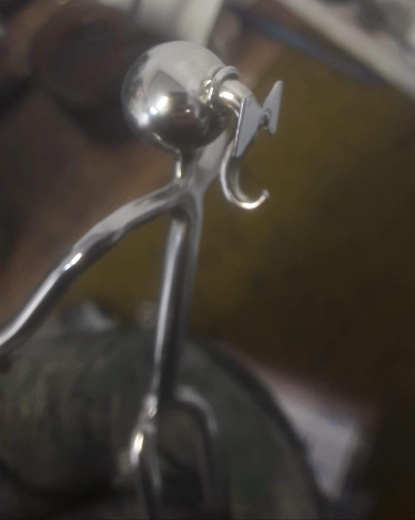 Detal nierdzewnej poręczy z kulistym zakończeniem i haczykiem mocującym, widoczne ślady obróbki metalu