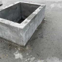 Surowy betonowy otw&oacute;r w stropie, prawdopodobnie przygotowany pod instalacje, z widocznymi śladami po deskowaniu i drobnymi fragmentami gruzu wok&oacute;ł.