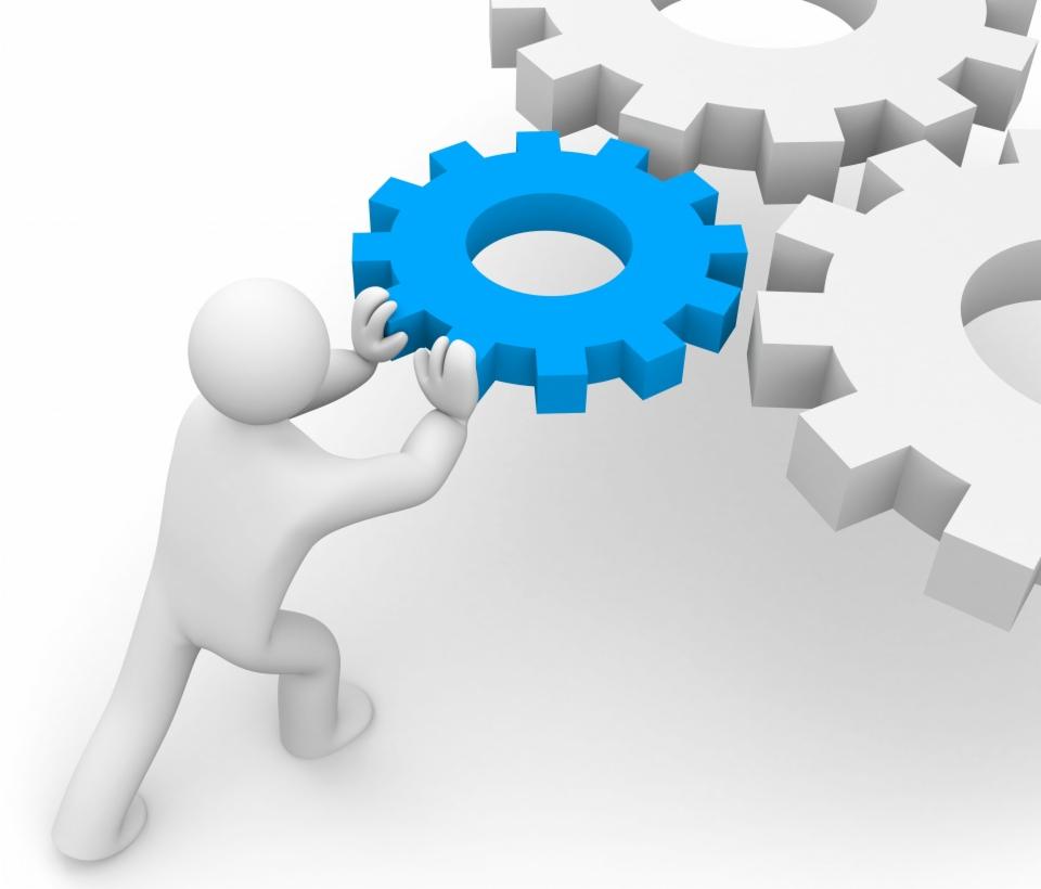 Animowana postać ustawia niebieskie koło zębate obok dwóch białych kół zębatych na białym tle, symbolizując mechanizm działania.