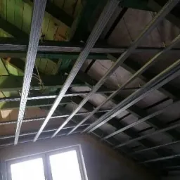 Konstrukcja metalowa sufitu podwieszanego z płyt kartonowo-gipsowych zamontowana na drewnianym stropie poddasza, widok od dołu.