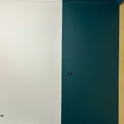 Ściana pomalowana na pół biało i na pół ciemnozielono, widoczne gniazdka elektryczne, listwa przypodłogowa, folia ochronna na podłodze.