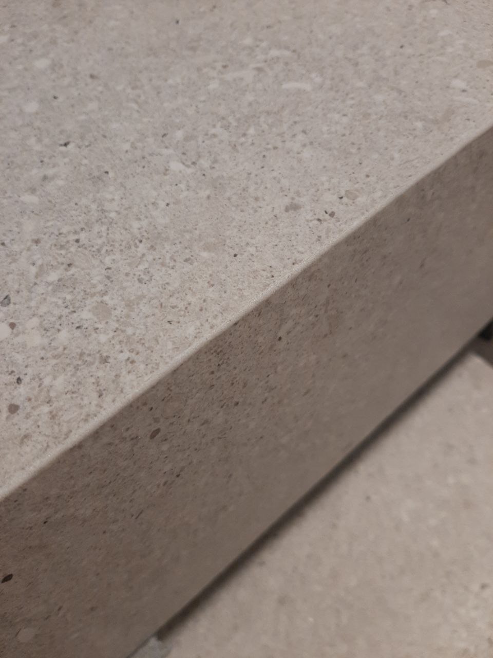 Szczegółowe ujęcie krawędzi blatu z konglomeratu kwarcowego w odcieniach szarości, ukazujące drobną strukturę i wykończenie powierzchni.