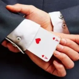 Mężczyzna w garniturze trzymający w mankiecie asa kier, sugerujący ukryte atuty lub nieuczciwość.