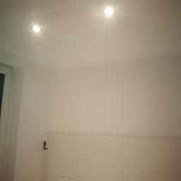 Brak - Świeżo pomalowane, białe ściany z zamontowanymi punktowymi lampami sufitowymi w mieszkaniu w Bytomiu, widoczne płytki na ścianie i gniazdka elektryczne.