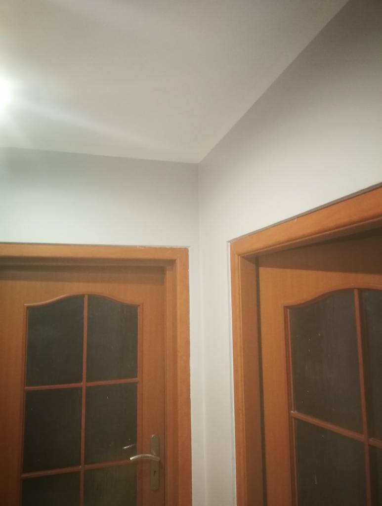 Fragment rogu pokoju po malowaniu ścian na szaro, widoczne dwie drewniane drzwi z szybami.