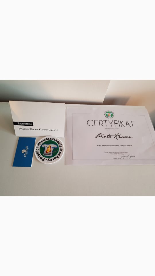 Zaproszenie na Sylwestra Szefów Kuchni i Cukierni, certyfikat kulinarny z podpisem, naszywka Stowarzyszenia Kucharzy Polskich i wizytówka na jasnym tle.