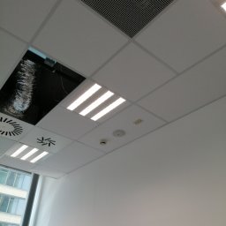 Art-Bud Remonty i Wykończenia - Sufit podwieszany z rastrem, oświetleniem LED i kratką wentylacyjną, widoczny fragment instalacji wentylacyjnej w otworze, czujnik dymu.