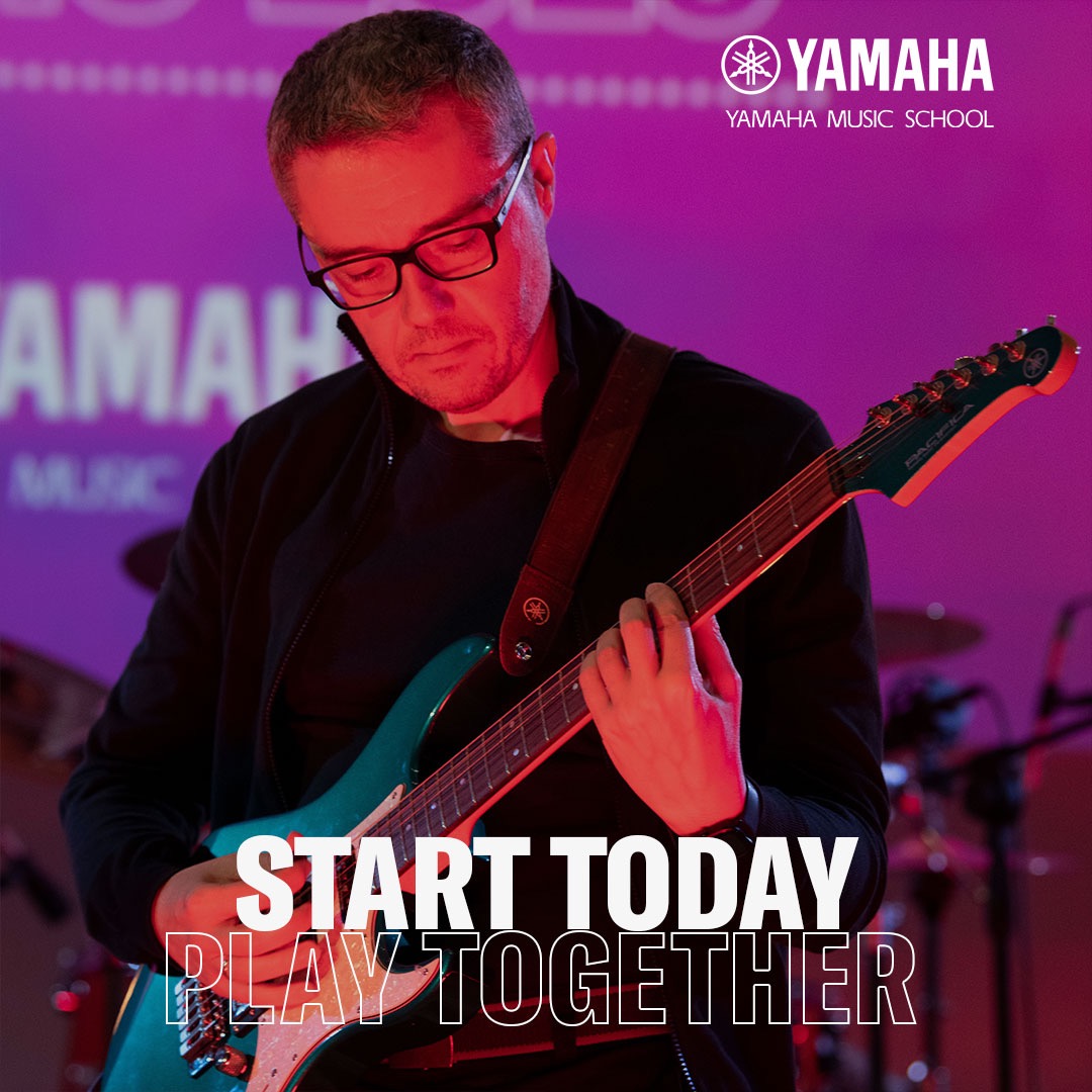 Mężczyzna w okularach gra na elektrycznej gitarze Yamaha Pacifica na tle fioletowej ściany z logo Yamaha Music School. Napis: Start Today, Play Together.