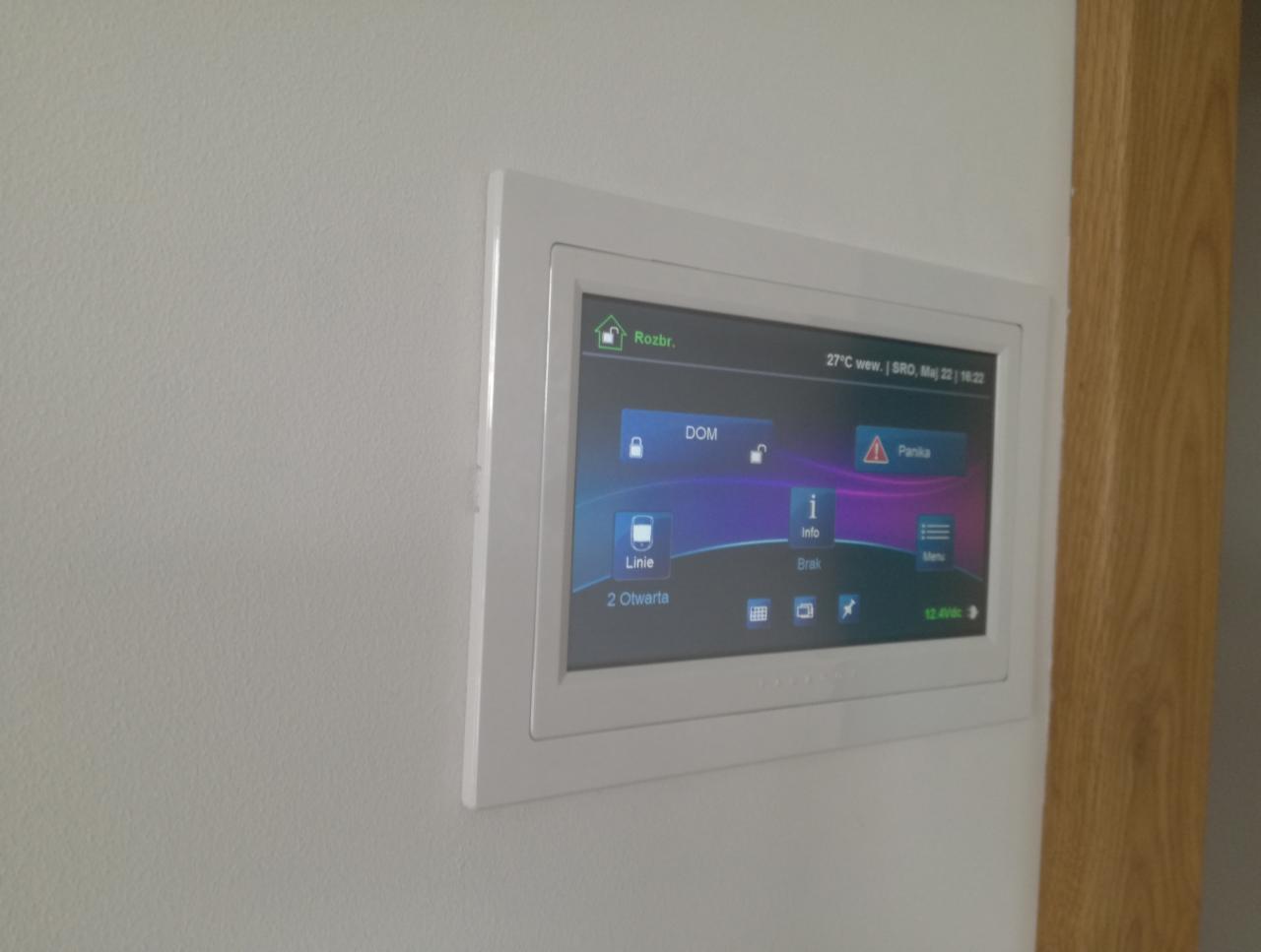 Panel sterowania systemem bezpieczeństwa domu, zamontowany na ścianie w Piasecznie, wyświetlający informacje o stanie systemu i temperaturze wewnętrznej.