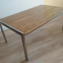 Prostokątny stolik kawowy z blatem z jasnego drewna i metalowymi nogami, ustawiony na podłodze z paneli imitujących drewno.