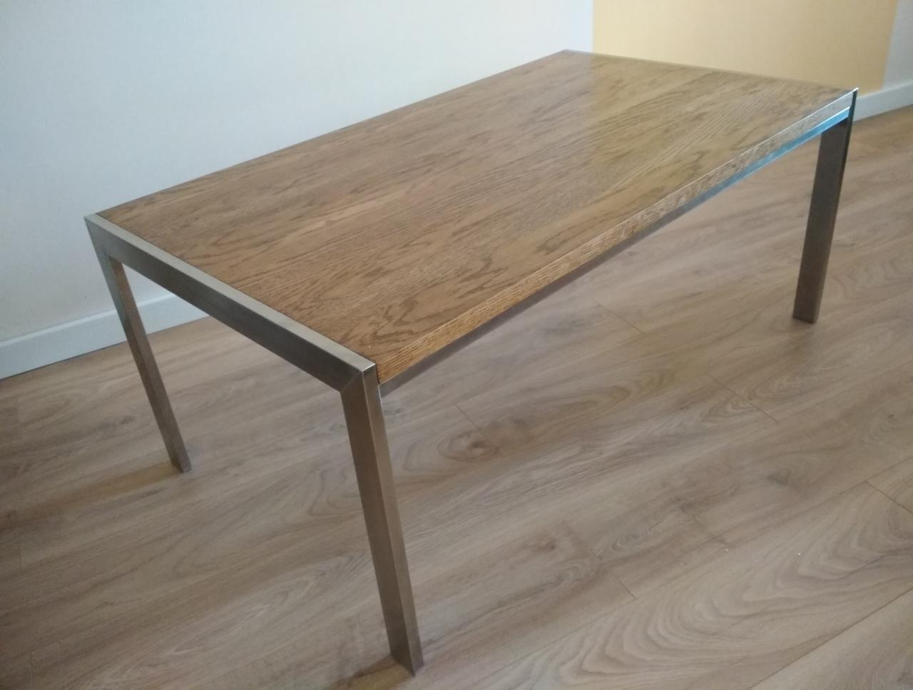 Prostokątny stolik kawowy z blatem z jasnego drewna i metalowymi nogami, ustawiony na podłodze z paneli imitujących drewno.