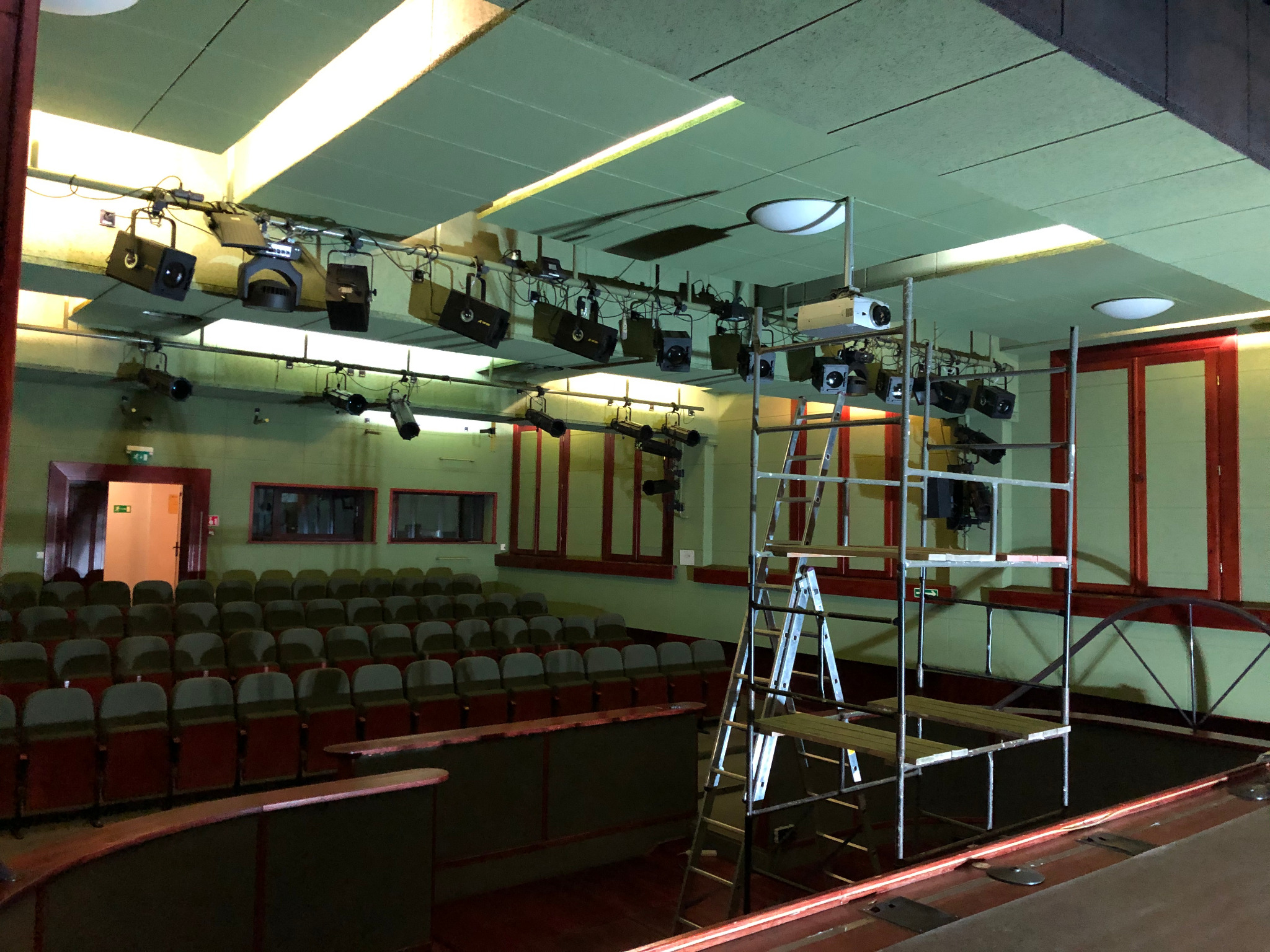Wnętrze sali widowiskowej w Będzinie podczas prac remontowych; widoczne rusztowanie, oświetlenie sceniczne i sufit z panelami akustycznymi, prawdopodobnie po świeżym malowaniu.