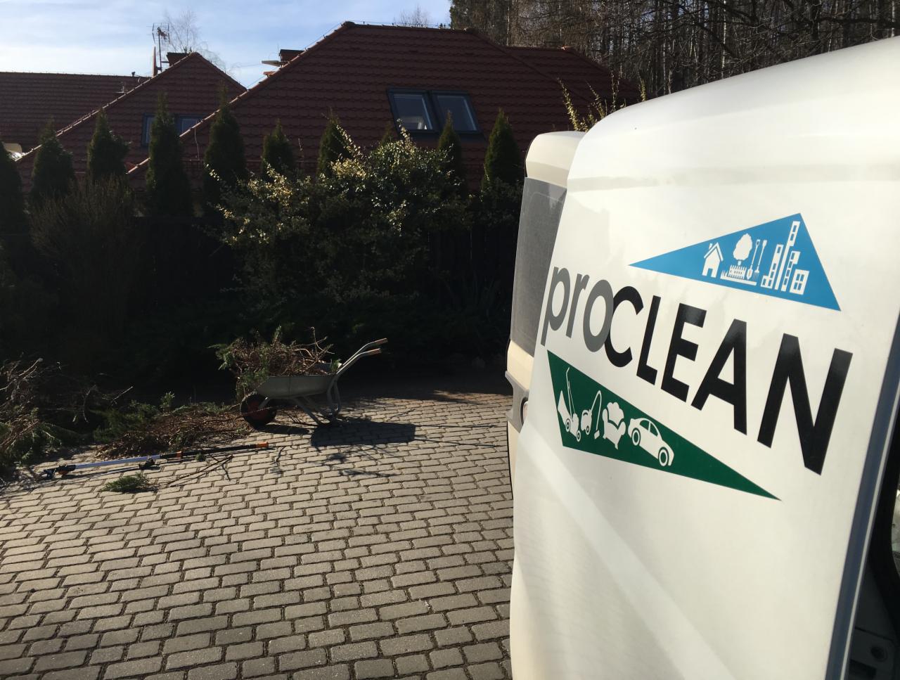 Furgonetka z logo firmy Proclean na tle posesji z przyciętymi gałęziami i taczką, sugerująca prace porządkowe na zewnątrz.
