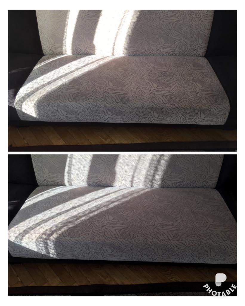 Sofa z jasną tapicerką w geometryczny wzór, oświetlona promieniami słonecznymi padającymi przez okno, widoczne cienie na siedzisku i oparciu.