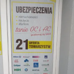 Żółto-biały plakat reklamowy w ramie, oferujący ubezpieczenia nieruchomości, na życie i dla firm, z informacją o tanich OC i AC oraz prezentacją logo 21 towarzystw ubezpieczeniowych i numerem...