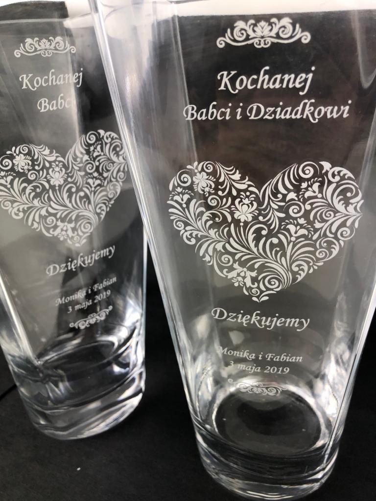 Dwa szklane wazony z grawerem: serce z ornamentami, napis 'Kochanej Babci i Dziadkowi', 'Dziękujemy', imiona Monika i Fabian oraz data 3 maja 2019.