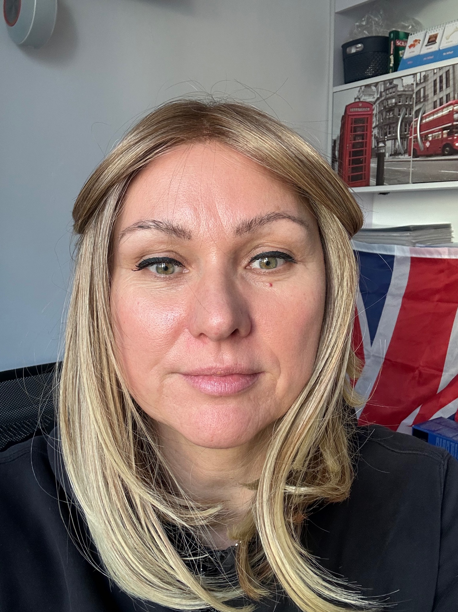 Portret kobiety z flagą Wielkiej Brytanii w tle, sugerujący naukę języka angielskiego. Widoczna półka z motywami londyńskimi.