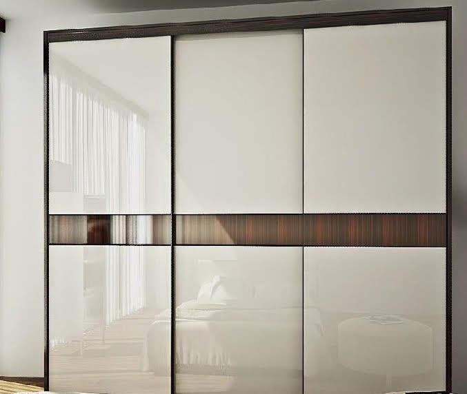 Nowoczesna szafa wnękowa z przesuwnymi drzwiami, z białymi panelami i poziomym pasem z ciemnego drewna, zamontowana w sypialni w Suwałkach, odbijająca w lustrze fragment łóżka i stolika.