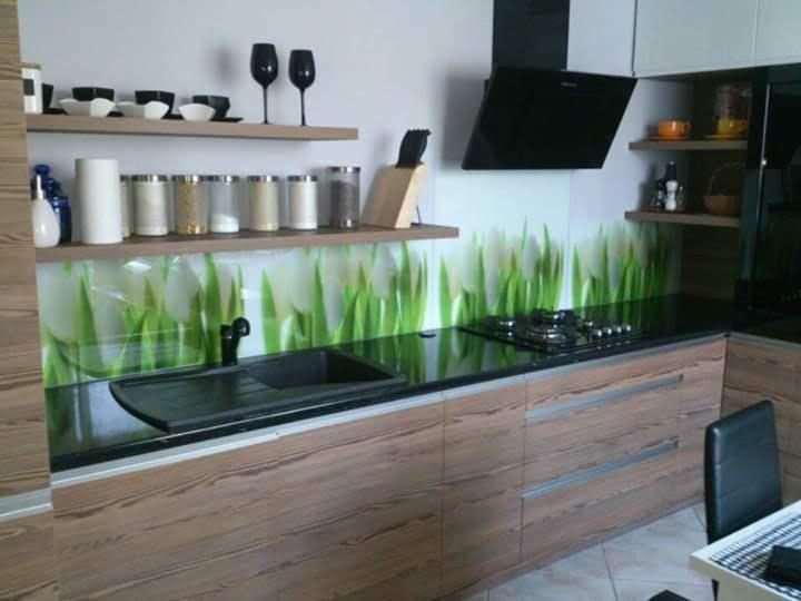 Nowoczesna kuchnia z drewnopodobnymi frontami, czarnym blatem i panelem szklanym z motywem tulipanów, widok na zlew, płytę grzewczą i okap