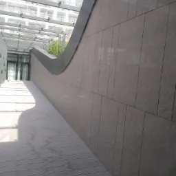 Elewacja budynku w Rotmance wykończona płytkami imitującymi kamień, z widoczną drewnianą podłogą i przeszklonym zadaszeniem.