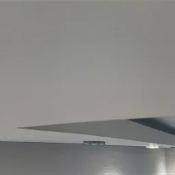 Narożnik ściany i sufitu po nałożeniu gładzi, widoczne niewielkie niedoskonałości wykończenia pod światło.