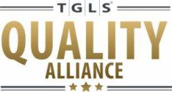 Złote logo TGLS Quality Alliance z czterema gwiazdkami u dołu, na białym tle.