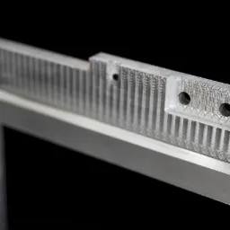 Szczegółowe zbliżenie metalowej ramy z precyzyjnie obrobionymi elementami, widoczne otwory i rowki, na czarnym tle.