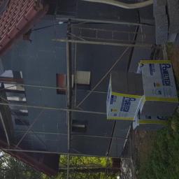 K&K BUD Usługi Remontowo Budowlane Malowanie /Tapetowanie/Zabudowy GK/Docieplanie/Ścianki Działowe itp - Ocieplanie elewacji domu jednorodzinnego styropianem grafitowym, widoczne rusztowanie i paczki materiału izolacyjnego Paneltech