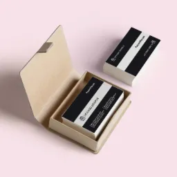 Kartonowe pudełko z kartami podarunkowymi 'Prezentmarzeń' o nominale 2000 PLN, ułożonymi w stos, oraz dodatkowy stos kart obok, na jasnoróżowym tle.