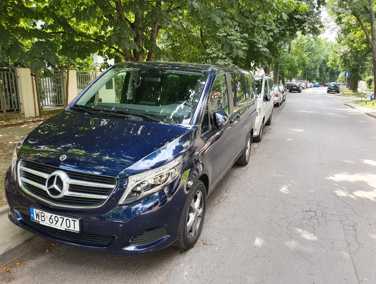 Niebieski van Mercedes-Benz zaparkowany na ulicy w Warszawie, widoczny znak zakazu parkowania na szybie.