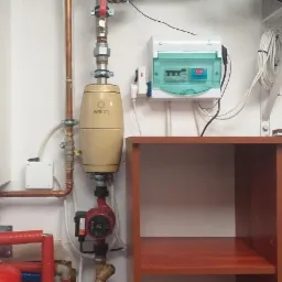 Zamontowana instalacja grzewcza z filtrem Wirco, pompą obiegową i rozdzielnicą elektryczną na białej ścianie, widoczne miedziane rury i elementy instalacji.