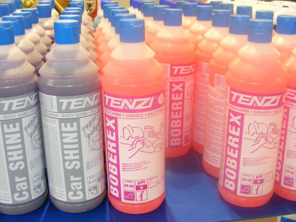 Rzędy plastikowych butelek z płynami do mycia, marki Tenzi i Boberex, etykiety z napisami w języku polskim, niektóre butelki szare z napisem Car Shine, inne pomarańczowe z napisem Geschirr Dishes...