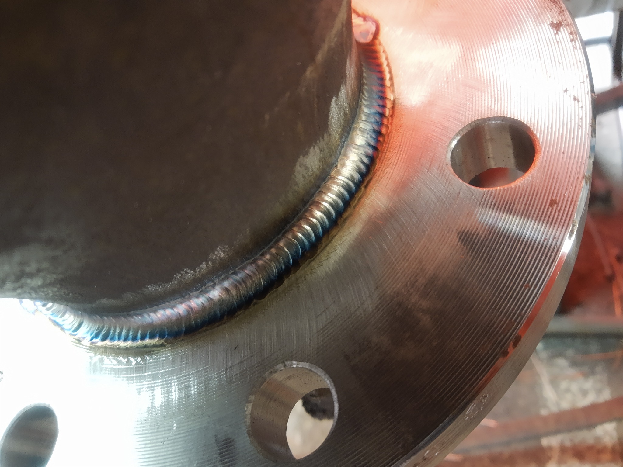 Spoina na metalowej rurze z widocznymi śladami ciepła i otworami na śruby