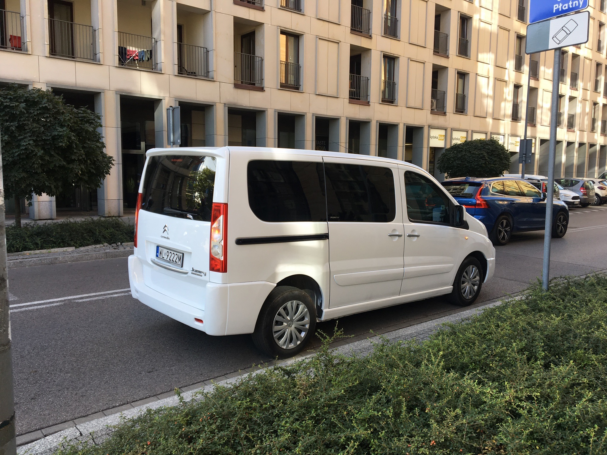 Biały Citroen Jumpy zaparkowany na ulicy, z widocznym numerem rejestracyjnym WL 9222M, na tle budynku z licznymi balkonami i znakiem drogowym 'Płatny'