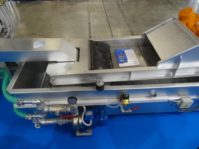 Szczegółowe ujęcie przemysłowej maszyny z elementami ze stali nierdzewnej, widoczne rury, pompa, manometr, oraz dokumentacja techniczna wewnątrz zbiornika.