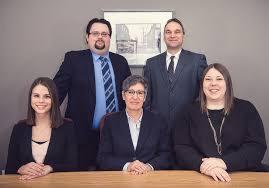 Grupa pięciu profesjonalnie ubranych osób (trzech mężczyzn i dwie kobiety) pozuje za biurkiem, z obrazem w ramie na ścianie w tle.