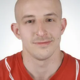 Portret łysiejącego mężczyzny w czerwonej koszulce z białymi paskami na jasnym tle, ujęcie od przodu, neutralny wyraz twarzy, widoczne detale skóry.