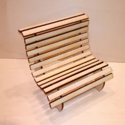 Miniaturowa drewniana ławka z laserowo wycinanych listewek, prezentowana na gładkim, drewnianym tle.