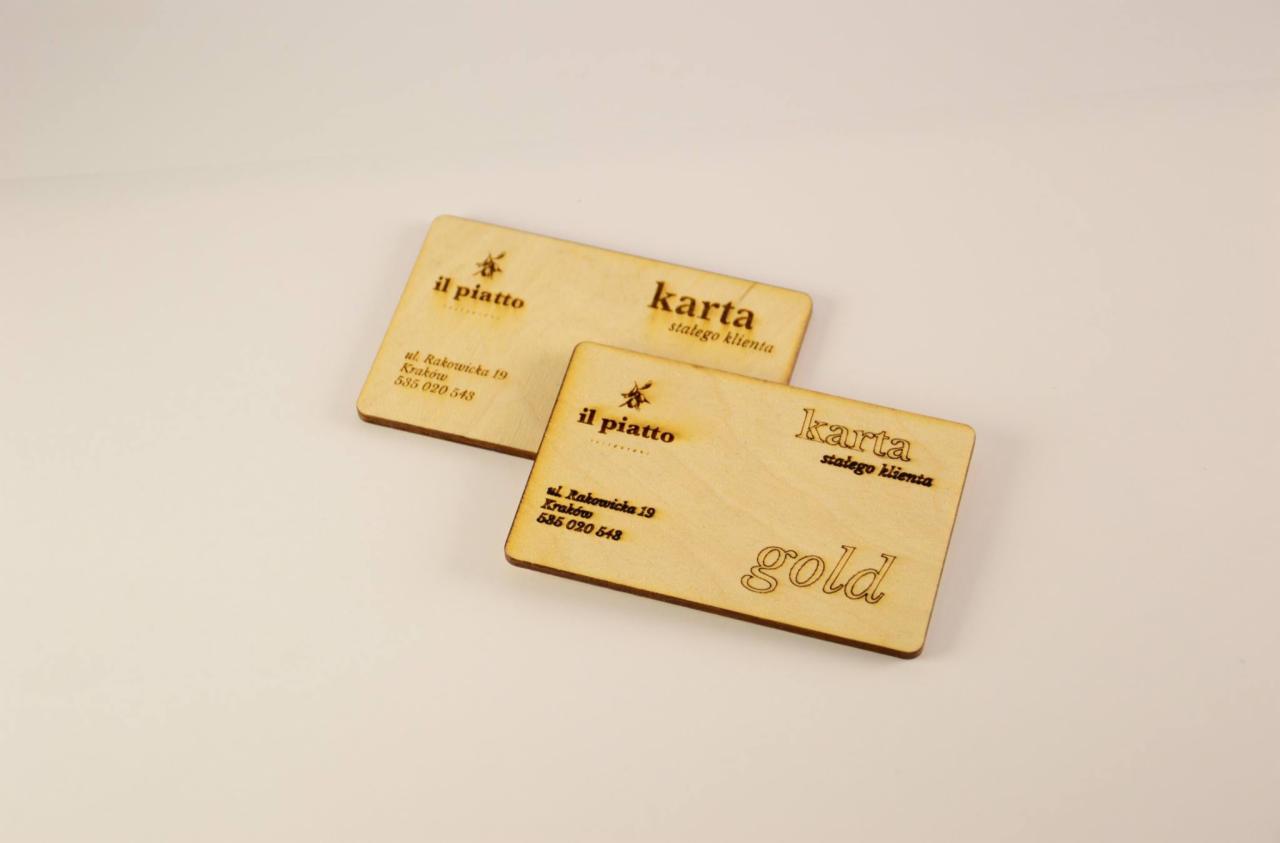 Dwie drewniane karty stałego klienta z wygrawerowanym logo 'il piatto', adresem w Krakowie i napisem 'gold' na jednej z nich.