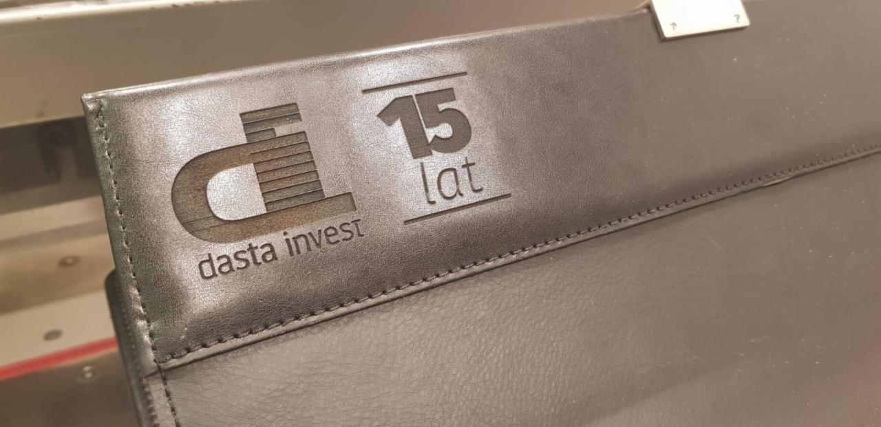 Czarna skórzana teczka z wytłoczonym logo firmy Dasta Invest, z napisem '15 lat', wykonana techniką laserową.