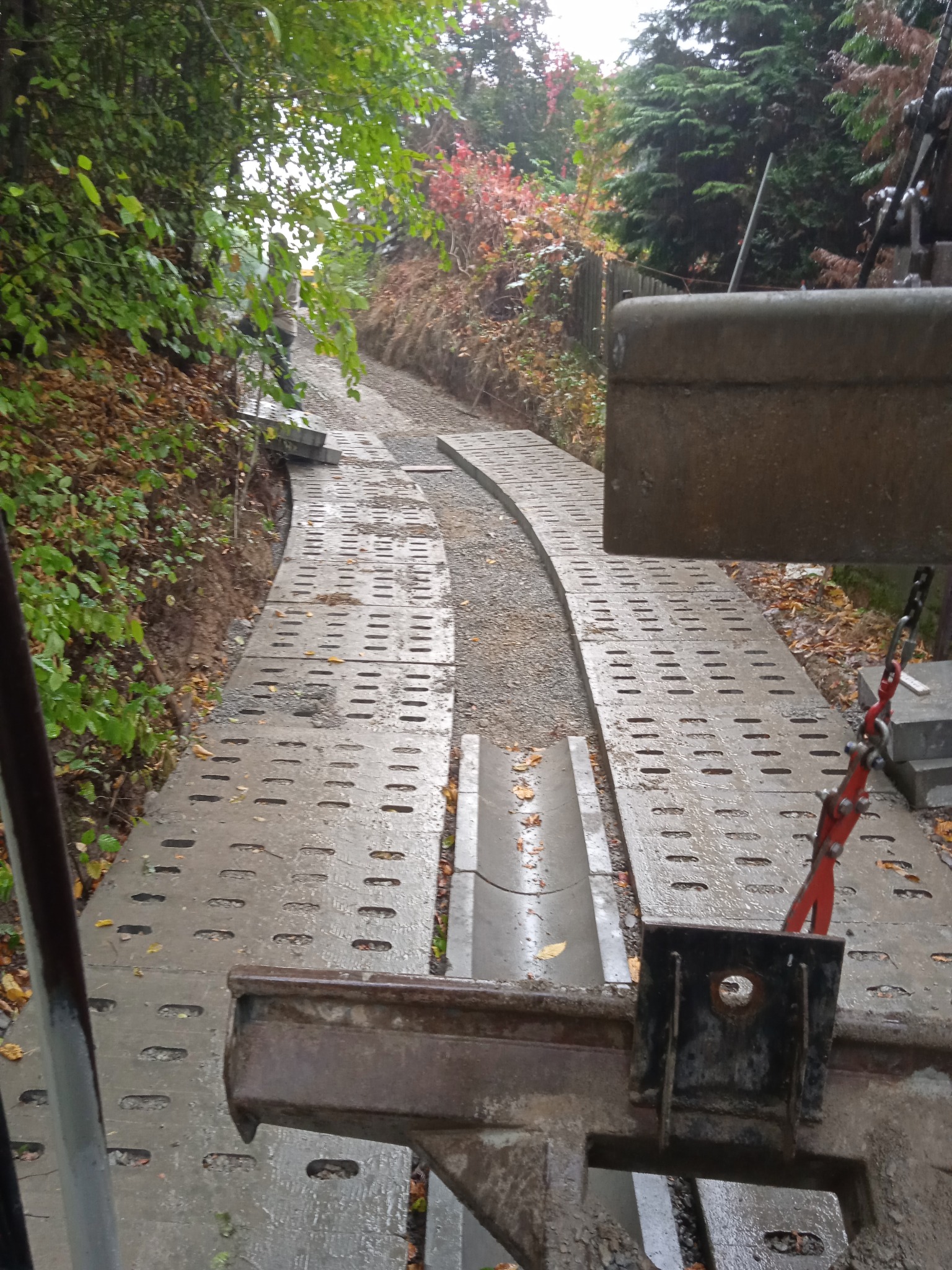 Przygotowanie podłoża pod drogę przez las z wykorzystaniem betonowych płyt ażurowych, widok z perspektywy maszyny budowlanej.