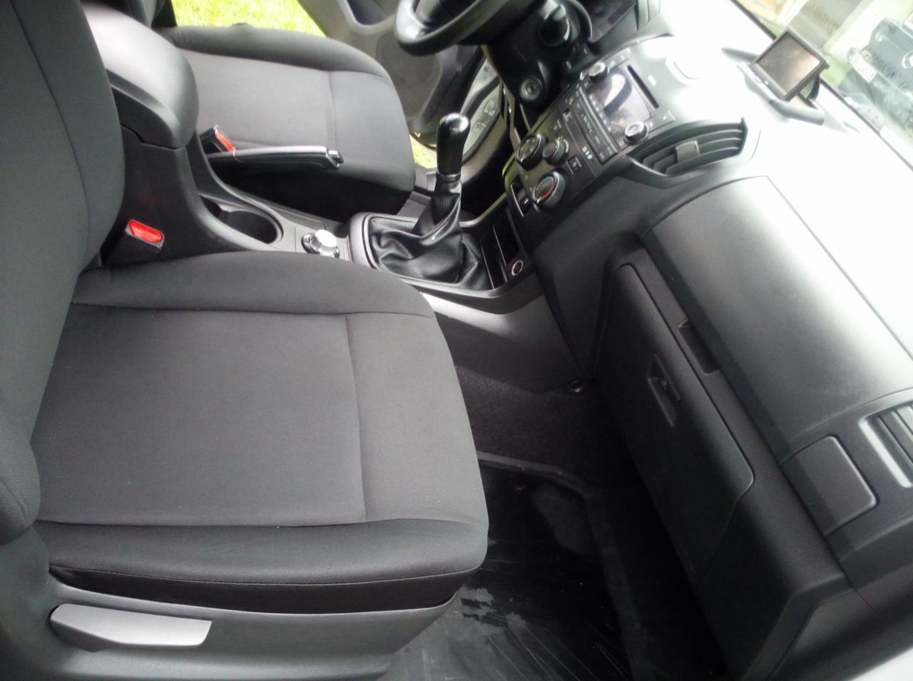 Wnętrze samochodu z czystymi, szarymi fotelami, czarną deską rozdzielczą i dźwignią zmiany biegów, widoczne detale tapicerki i elementów sterowania.