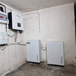 FotonSolar - Instalacja magazynu energii Triple Power i falownika Solax w pomieszczeniu o surowych ścianach. Widoczne okablowanie i elementy montażowe.